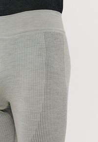 Leggings atléticos cinzentos com um design texturizado em padrão de grelha, um cós suave e tecido respirável com discretos acabamentos em rede.