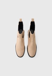 Μπεζ σουέτ μπότες μέχρι τον αστράγαλο με λεία υφή, ελαστικές πλαϊνές επενδύσεις, λαβές και μαύρη ελαστική σόλα, σε όψη από πάνω.