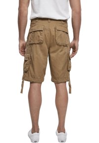 Shorts cargo beiges avec plusieurs poches latérales, une coupe décontractée et des cordons ajustables à l'ourlet. Fabriqués en tissu de coton durable.