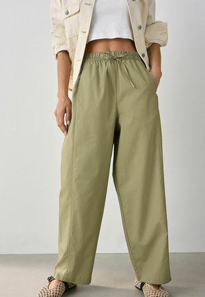 Pantaloni ampi di un verde oliva chiaro, con vita elastica e laccetto. Realizzati in un tessuto leggero e morbido. Presentano tasche laterali.