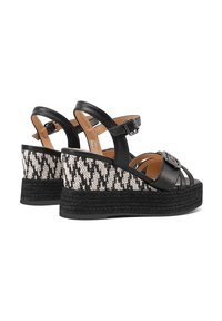 Sandali con zeppa nera in pelle, con tessuto intrecciato a motivo nero e bianco. Cinturino alla caviglia regolabile e dettaglio decorativo con fibbia.