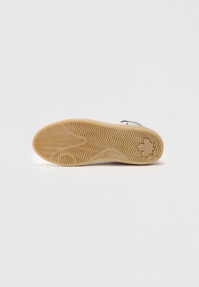 Suela de zapato con un patrón de espiga, hecha de goma, en color beige con una superficie texturizada y una impresión del logo de la marca.