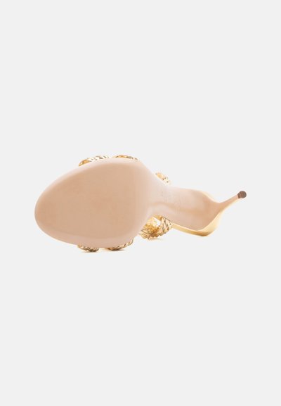 Γυναικείο σανδάλι με ψηλό τακούνι, που φαίνεται από τη σόλα προς τα πάνω, με μυτερή μύτη, λεπτό τακούνι και χρυσά πλεγμένα λουριά.