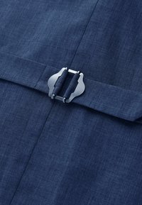 Tissu bleu foncé avec un gros plan d'une boucle métallique argentée fixant une sangle en tissu assortie.