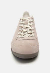 Sneakers en daim rose clair avec bout rond, lacets blancs contrastants avec des éclats rouges, semelle en caoutchouc plate et détails cousus.
