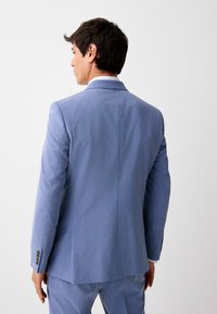 Helles blaues Sakko mit strukturiertem Design, einzelnen Schlitz und Knopfdetails mit drei Knöpfen. Aus strukturiertem Stoff, taillierte Passform.