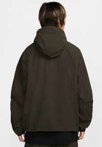 Giacca a cappuccio verde scuro con un design leggero, caratterizzata da una vestibilità comoda, polsini elasticizzati e una superficie in tessuto liscia.