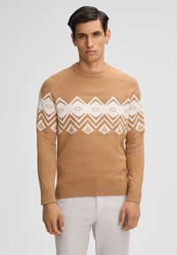 Beżowy sweter z dzianiny z białym geometrycznym wzorem na klatce piersiowej, okrągłym dekoltem oraz ściągaczami przy mankietach i dolnej k rawędzi.