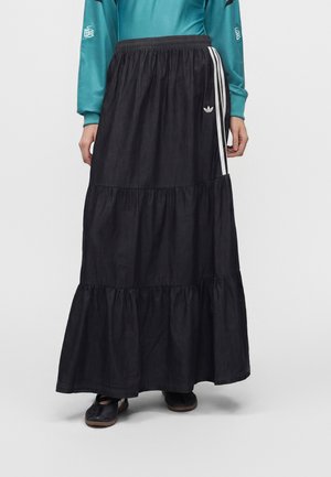 Schwarzer gestufter Maxirock mit elastischem Bund, Adidas-Logo und weißen Streifen an der Seite, getragen mit einem türkisfarbenen Langarmshirt und schwarzen Schuhen.