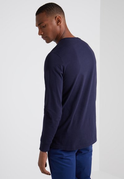 Marineblauw shirt met lange mouwen van katoen, voorzien van een klassieke ronde hals, rechte zoom en geribbelde manchetten, gedragen met blauwe broek.