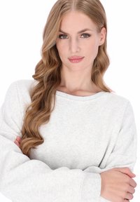 Lichtgrijze trui met een brede halslijn en geribbelde manchetten. Zachte textuur, lange mouwen, losse pasvorm, minimalistisch ontwerp zonder zichtbare patronen.