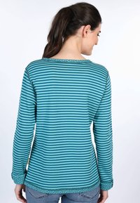 Gestreiftes Langarmoberteil in Teal und Hellblau, mit dekorativem Besatz am Halsauschnitt und den Ärmeln sowie einer lockeren Passform.