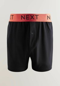 Fekete pamut boxer short, sima tapintással, narancssárga rugalmas derékpánttal, amelyen fekete betűkkel szerepel a "NEXT" felirat.