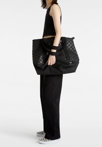 Svart rutigt tote bag med dubbla svarta handtag, tillverkat av hållbart material. Väskan har en rymlig design och en platt botten för stabilitet.