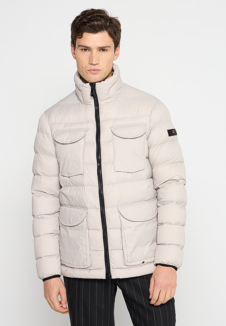 Giacca imbottita beige chiaro con colletto alto, chiusura a zip e quattro tasche frontali. Presenta una zip nera a contrasto e un sottile accento del logo.
