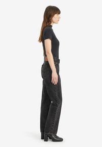 Zwarte high-waisted jeans met een rechtlopende snit, gecombineerd met een fitted top met korte mouwen in marineblauw. Opaque textuur; gladde stofafwerking.