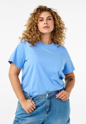 Helles blaues Baumwoll-T-Shirt mit kurzen Ärmeln und einem runden Halsausschnitt, kombiniert mit hochgeschnittenen blauen Jeansshorts. Minimalistisches Design, glatte Textur.