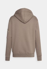 Sweat à capuche de couleur taupe douce, fabriqué en tissu lisse avec une poche kangourou. Comprend des poignets côtelés et un détail de poche latérale.