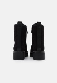 Bottines en daim noir avec une finition texturée, fermetures éclair latérales doubles, panneaux élastiques et un talon épais strié.