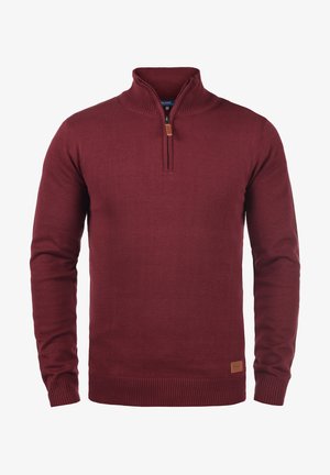 Bordorød strikkegenser med kvart-zip krage, ribbede mansjetter og kant, med et lite brunt skinnmerke på nedre venstre side.