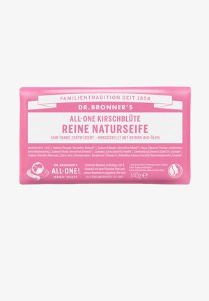 Die Seifenbar von Dr. Bronner ist rechteckig und hat eine pinkfarbenen Verpackung mit weißen Text und dem Erdenlogo. Sie trägt das Fair Trade-Siegel sowie eine Zutatenliste.