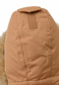 Chaqueta acolchada con capucha y borde de pelaje sintético. Presenta un tejido resistente, costuras cosidas y un cierre de gancho y bucle en la parte superior.