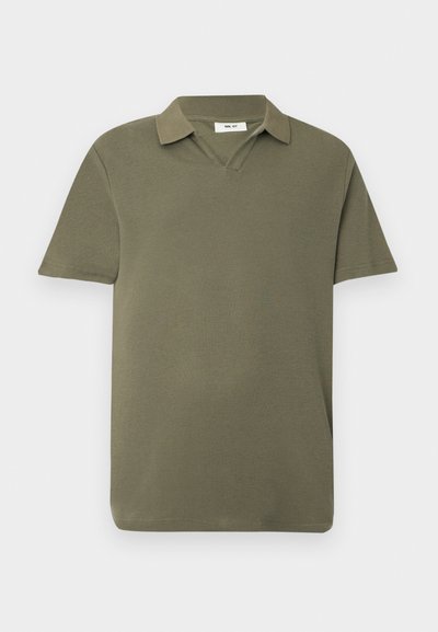 Polo vert olive à manches courtes avec un tissu texturé et un col doux, présenté sur un fond clair uni.
