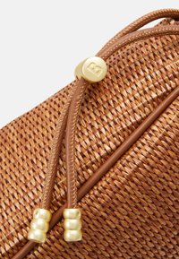 Bruine gevlochten tas met een textuur oppervlak, leren accenten en een gouden metalen sluiting met decoratieve kraal details.