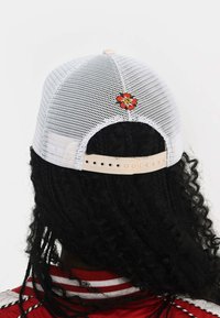 White mesh baseball cap featuring an embroidered red flower detail on the back, with a tan adjustable strap at the rear.