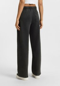 Pantalons de survêtement à jambes larges en doux tissu gris. Dotés d'une taille élastique, d'une poche arrière et de poignets côtelés au bas.