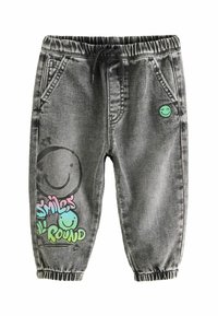 Grå denimjoggers med elastisk midja och mudd. Har färgglada smiley face-grafik och text på vänstra benet. Två framfickor.