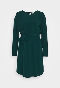 Ciemnozielona sukienka z długim rękawem, okrągłym dekoltem, detalem w postaci przewiązki w talii oraz wycięciem na plecach. Wykonana z gładkiego materiału, długość sięgająca do kolan.