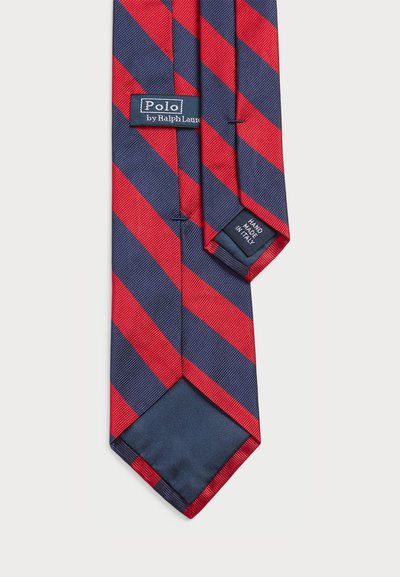 Sarkans un jūras spēku krāsā svītrots kaklasaites izgatavota no gludas auduma. Iekļauti tagi "Polo by Ralph Lauren" un "Handmade in Italy". Trīsstūra formas gals.