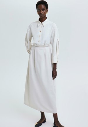 Witte linnen shirtjurk met een gekraagde halslijn, knoopsluiting aan de voorkant, ceintuur op de taille en volumineuze mouwen; soepel, elegant ontwerp.