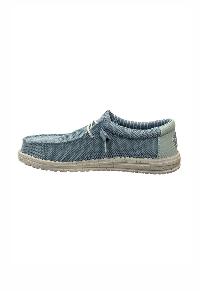 Scarpa slip-on in rete blu con accenti bianchi, suola piatta e tessuto texturizzato. Presenta una punta arrotondata e un dettaglio di allacciatura decorativa.