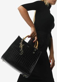 Borsa nera in pelle con texture a coccodrillo, con manici in bambù, accessori dorati e un charm decorativo a forma di '3'. Finitura lucida e design strutturato.