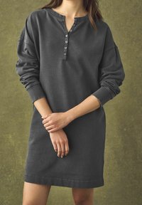 Robe henley grise à manches longues avec une patte de boutonnage et des poignets côtelés ; tissu doux, coupe ample, longueur mi-cuisse, avec un col rond.