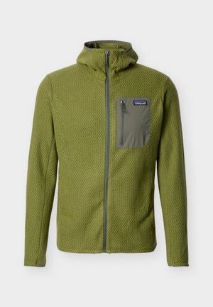 Φωτεινό πράσινο υφασματένιο φλις μπουφάν με φερμουάρ και ψηλό γιακά, με σκούρο πράσινο τσεπάκι στο στήθος με φερμουάρ στην αριστερή πλευρά.