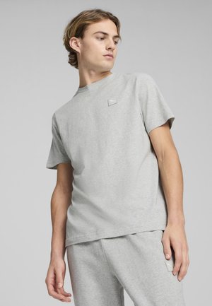 Grijze t-shirt met korte mouwen, gemaakt van zacht materiaal. Heeft een klein logo-patch op de borst en een ontspannen pasvorm. Eenvoudig, minimalistisch ontwerp.