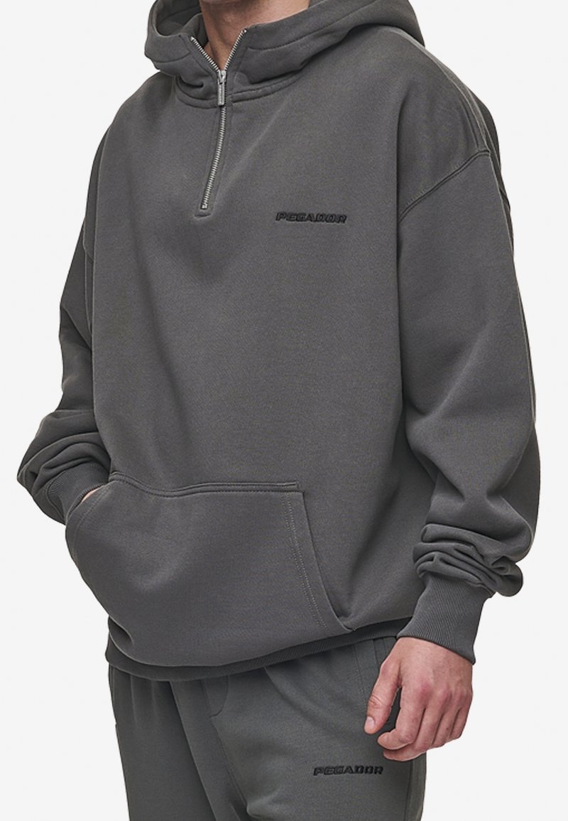 Grijze hoodie met een hoge kraag en een halflange rits. Heeft een voorzak met kangoeroe-ontwerp en een geborduurd "PEGADOR"-logo op de borst.