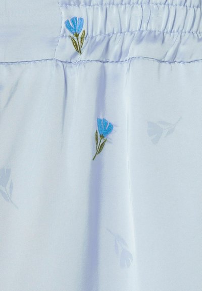 Tessuto azzurro chiaro con fiori ricamati in azzurro chiaro e verde. Presenta una texture morbida e un delicato motivo floreale sullo sfondo.