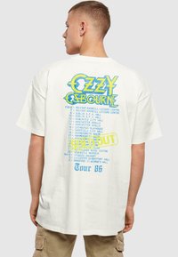 White cotton t-shirt featuring multicolored graphics on the back, listing concert dates and "SOLD OUT" in a bold, highlighted style.