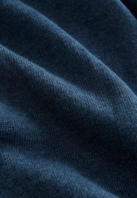 Marineblå strikket stof med en blød tekstur, der har et ribbet mønster og en let glans, som viser bløde bølgende folder.