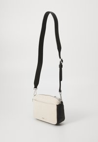 Texturerad vit tyg crossbody-väska med svarta läderdetaljer, silverfärgad hårdvara och en justerbar svart rem; rektangulär form.