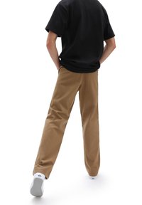 Khaki kalhoty vyrobené z odolné tkaniny, s rovnými nohavicemi a bočními kapsami, v kombinaci s černým tričkem a bílými teniskami.