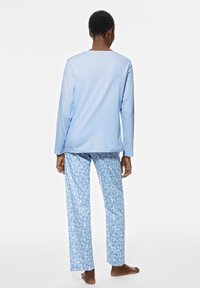 T-shirt à manches longues bleu clair associé à un pantalon de pyjama bleu clair à motifs floraux. Tissu doux avec une coupe décontractée et un design à jambe droite.