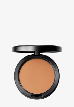 Kompakt sort makeup-etui åbnet, der afslører medium beige pudder i pres på ensfarvet hvid baggrund.