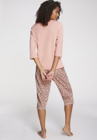 Light pink, three-quarter sleeve top paired with patterned, ankle-length pants featuring a leopard print in shades of brown.