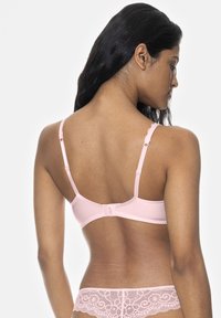 Ljusrosa bh med justerbara band, en slät kupa och en krok-och-ögla stängning. Spetsdetalj accentuerar den nedre banden.