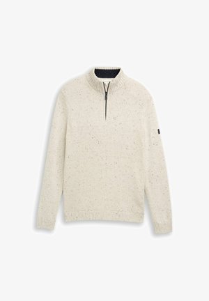 Sweter z dzianiny w kolorze kremowym, w czerwone plamki, z pół-zamkiem, prążkowanym wysokim kołnierzem, mankietami i dołem, wyeksponowany na białym tle.